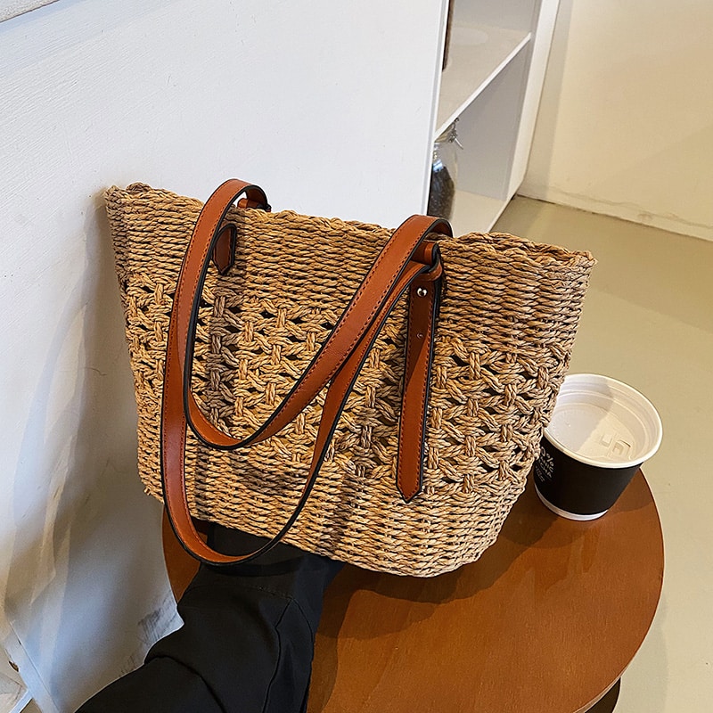 Structured handwoven straw handbag – brown variant, worn by a model