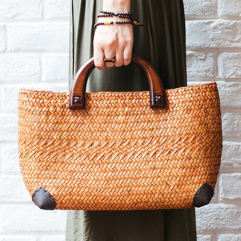 Elegant rattan tote with polished wooden handles – worn by a model