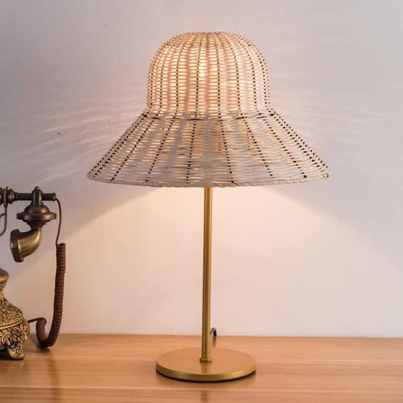 Rattan desk lamp with a handwoven hat-shaped shade – beige variant, shown lit