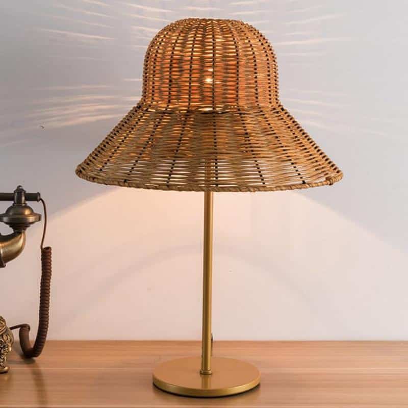 Rattan desk lamp with a handwoven hat-shaped shade – brown variant, shown lit
