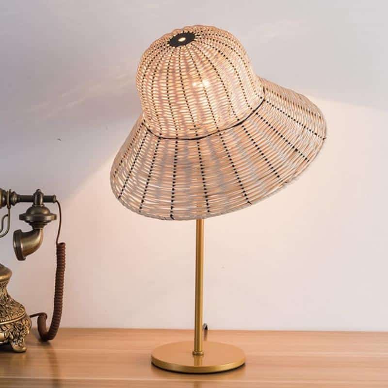 Rattan desk lamp with a handwoven hat-shaped shade – shown lit (2)