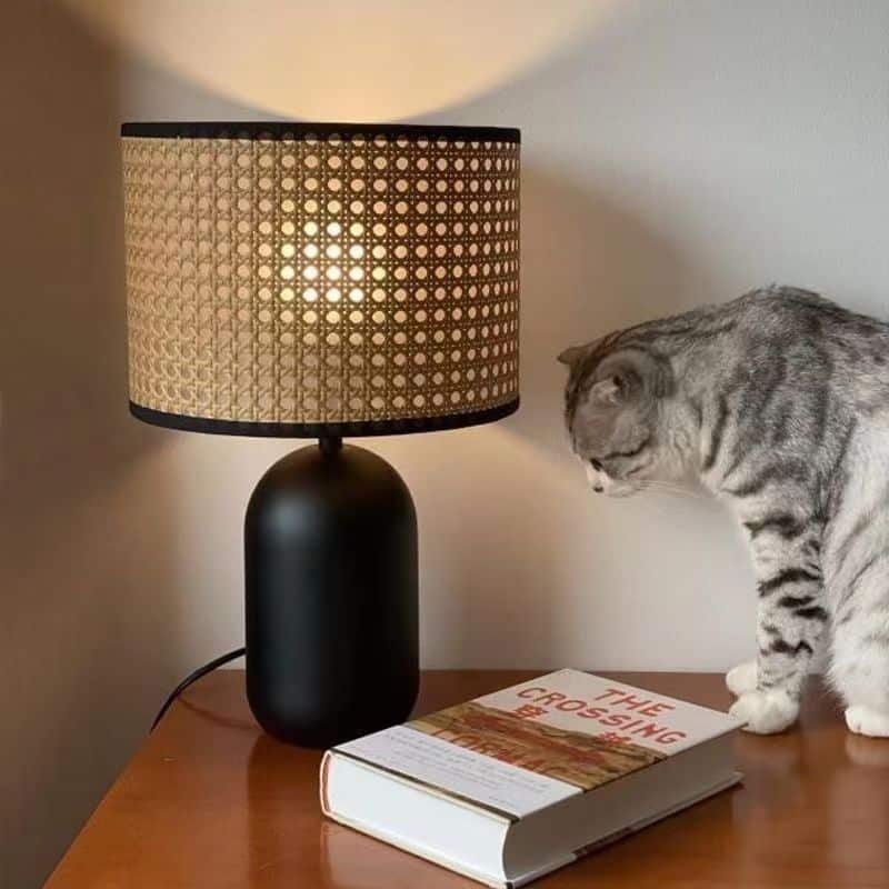 Rattan LED desk lamp with a handwoven shade and black metal base – shown in a room setting (4)