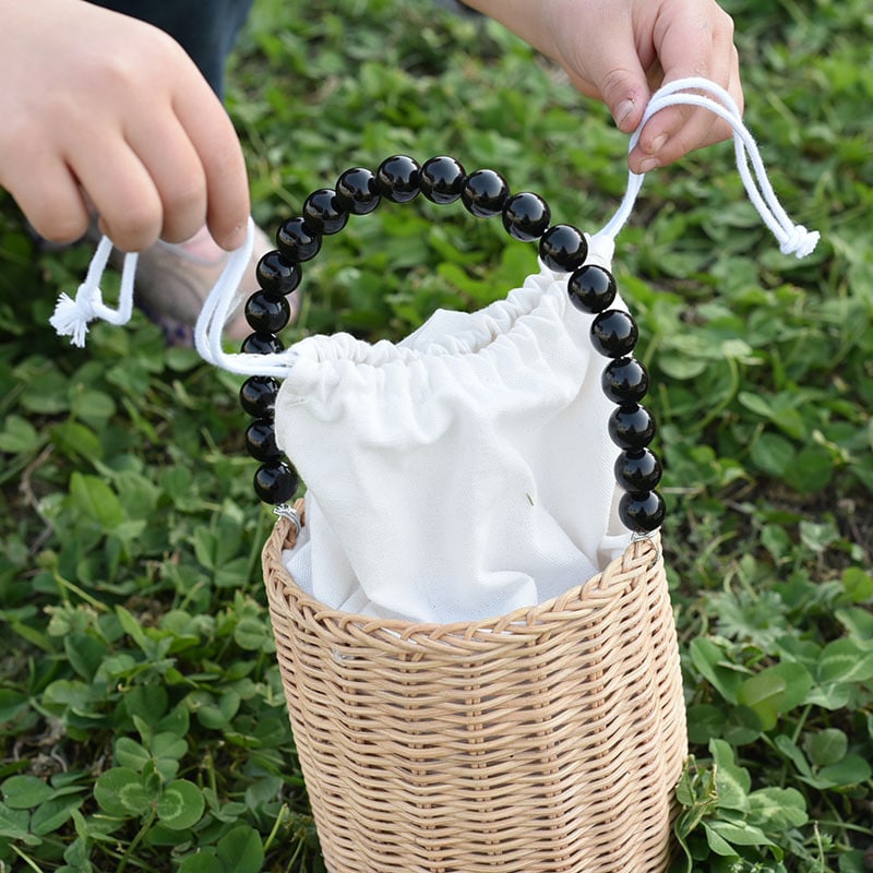 Kids woven storage basket with a beaded handle – shown outdoors