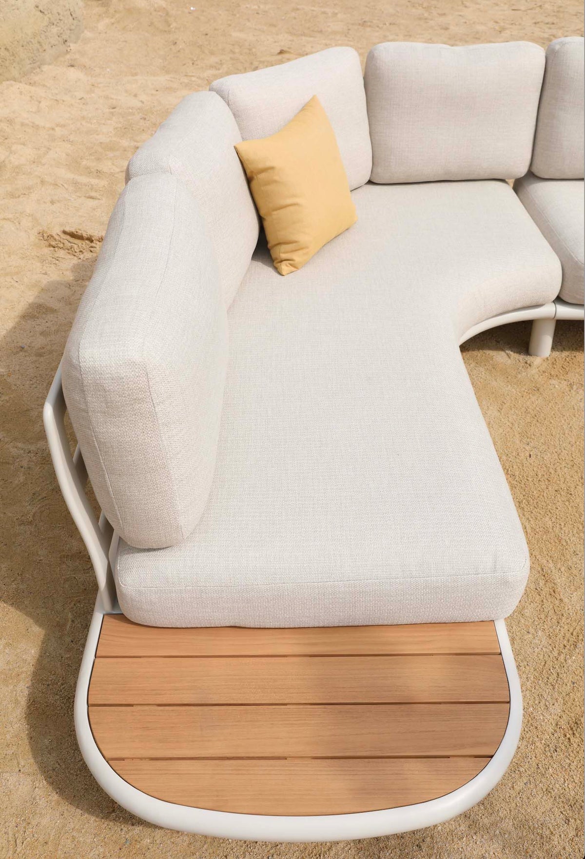 Chaise from the Sanka Cosy curved beige aluminum corner sofa with integrated teak platform – shown outdoors