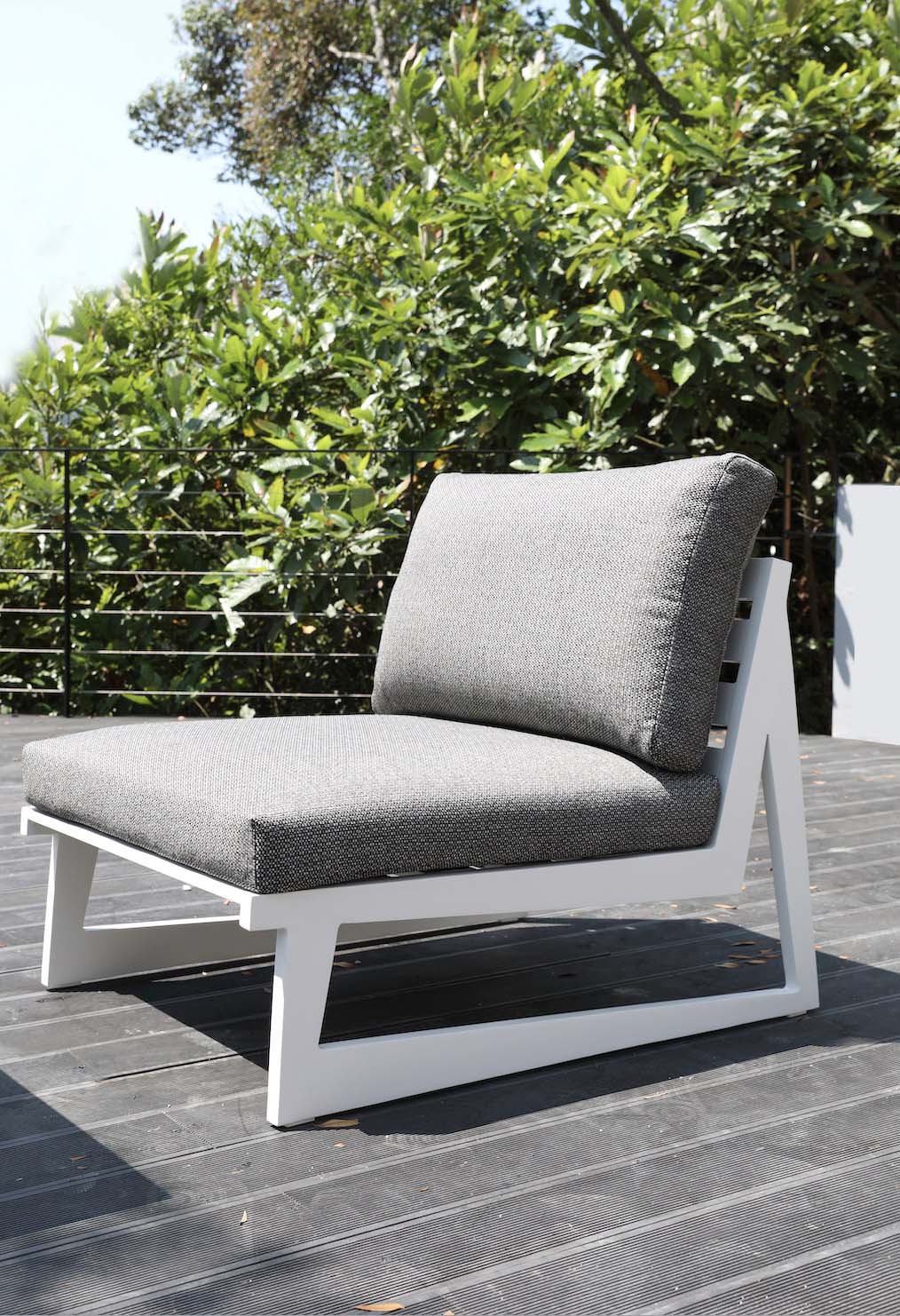 Armless chair from the Leo 7-seat white aluminum L-shaped outdoor sectional with gray cushions – shown outdoors