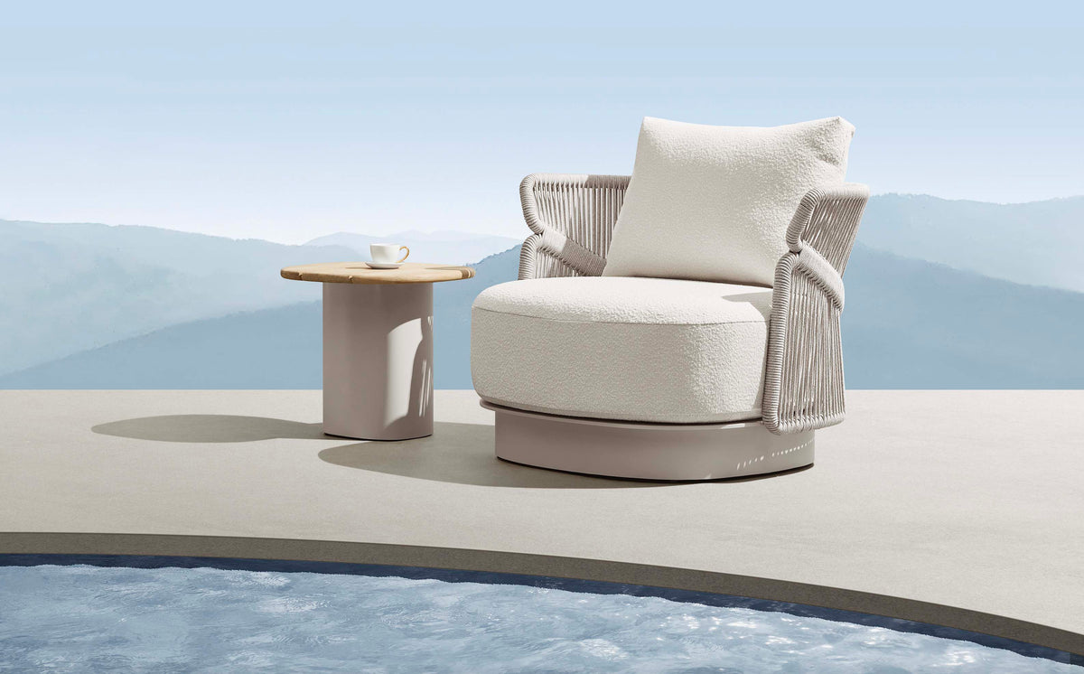 Armchair from the Laska beige aluminum and rope patio set with three teak-top tables – shown outdoors