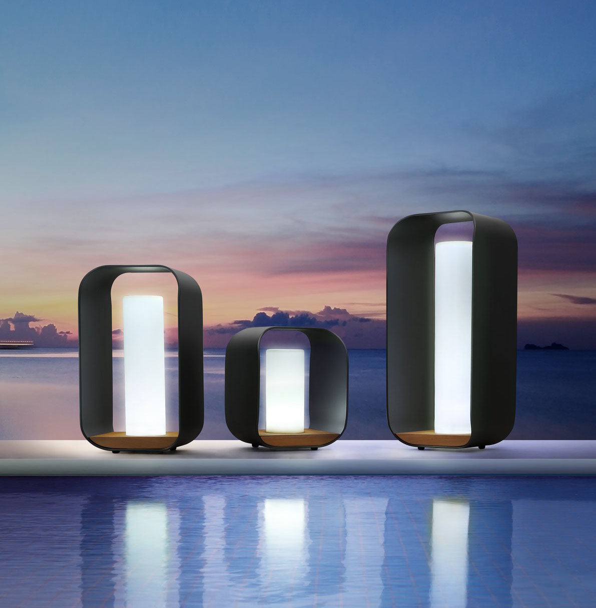 Onda black aluminum and teak cordless outdoor lamp – shown lit outdoors (2)