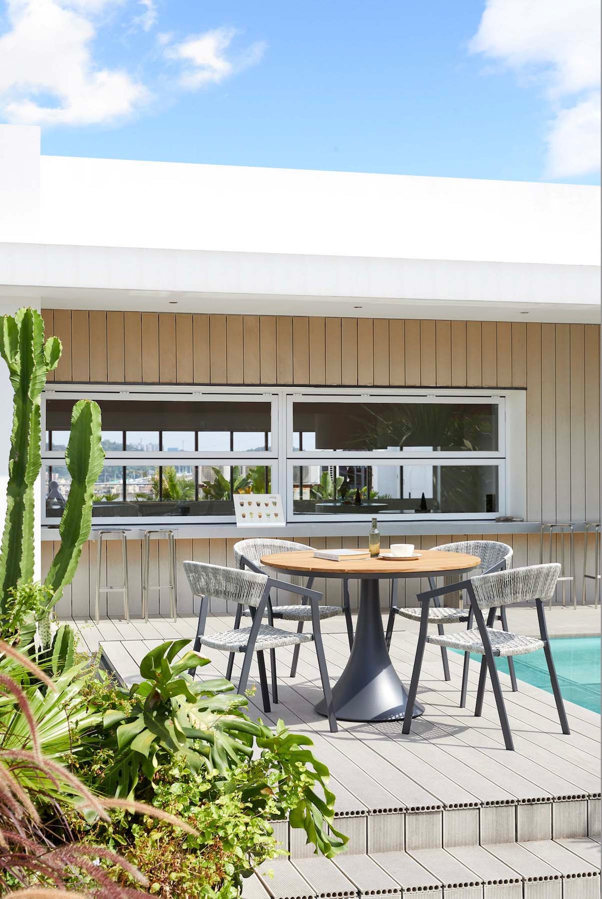 Fano black aluminum round teak-top patio table – shown outdoors (5)