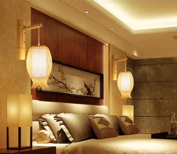 Handwoven round rattan wall sconce with a cascade of fringe – shown lit in a room setting