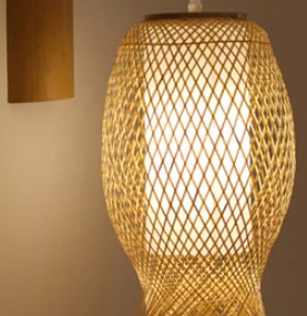 Handwoven round rattan wall sconce with a cascade of fringe – shown lit
