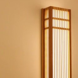 Handwoven rectangle rattan wall sconce with a warm natural finish – shown lit (2)