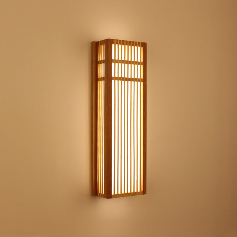 Handwoven rectangle rattan wall sconce with a warm natural finish – shown lit