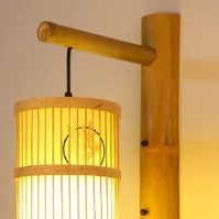 Cylindrical rattan wall sconce with an Asian-inspired woven pattern – shown lit (2)
