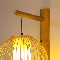 Round rattan wall sconce with an Asian-inspired woven pattern – shown lit (2)