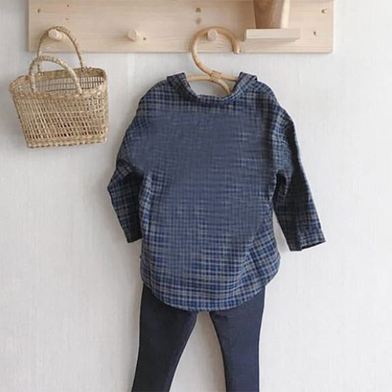 Hand-braided rattan clothes hanger with curved shoulders – shown in a room setting