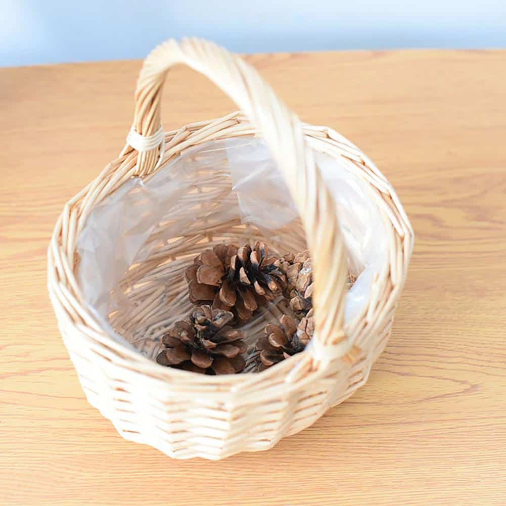 Beige round handwoven rattan basket with a sturdy handle – shown in a room setting