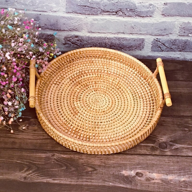 Handwoven rattan serving tray with light wood handles – shown in a room setting (2)