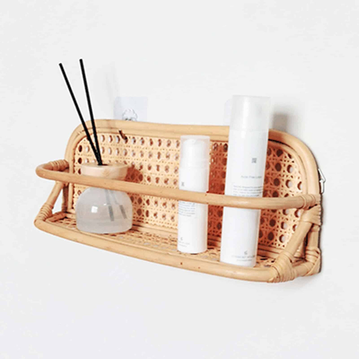 Hand-braided rattan wall hanger with metal hooks – shown in a room setting