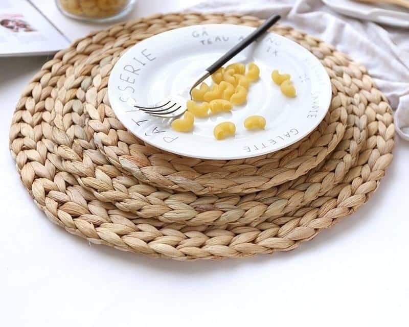 Round woven natural rattan trivet – shown in a room setting (3)
