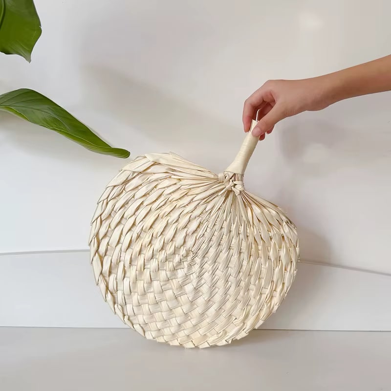 Retro half-circle rattan fan with a knotted handle – shown in use