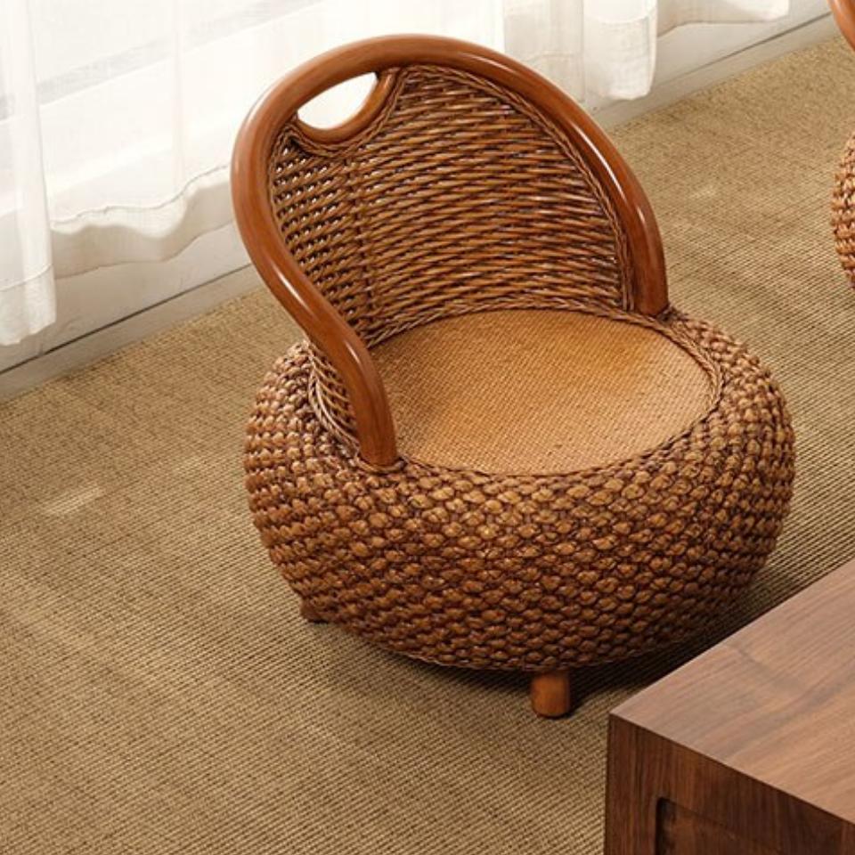 Small low brown rattan armchair with rounded shapes – shown in a room setting