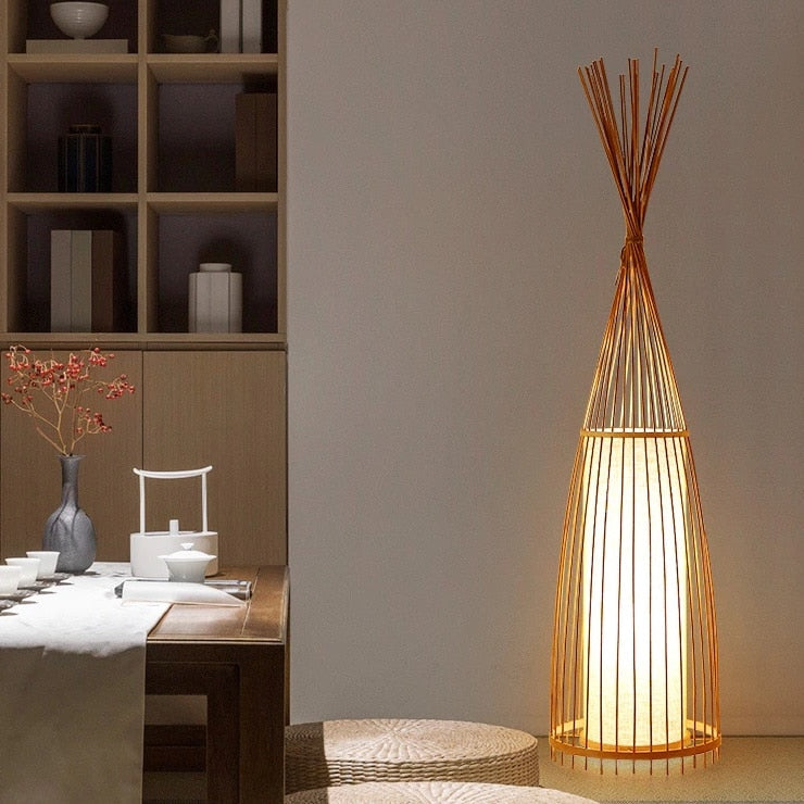 Handmade triangular rattan floor lamp with a tight weave – shown lit in a room setting