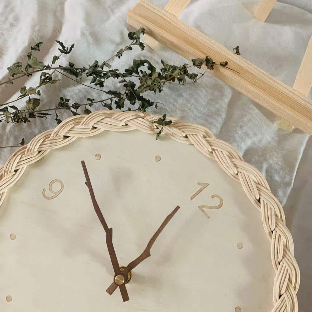 Round braided rattan wall clock with branch-shaped hands – shown in a room setting (3)