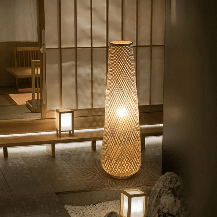 Nordic wicker-look floor lamp with a woven shade and slim metal stem – shown lit in a room setting