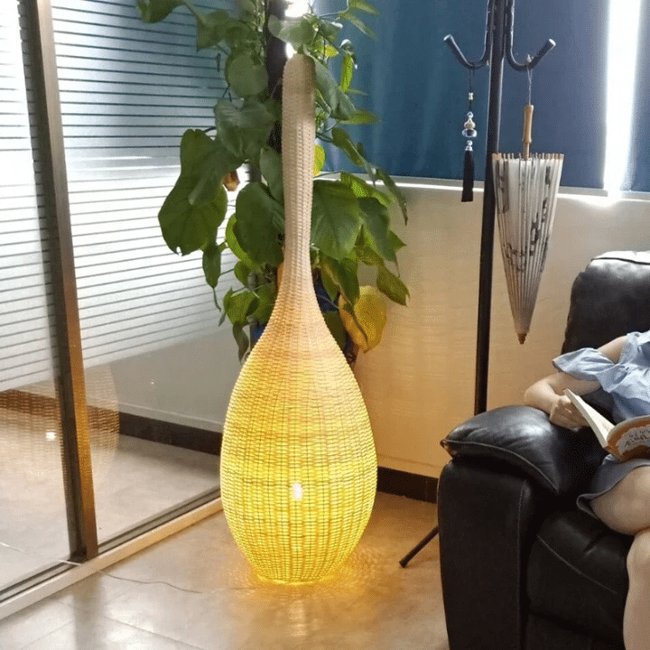 Japanese-style free-standing wicker LED floor lamp with a natural wood base – shown lit in a room setting