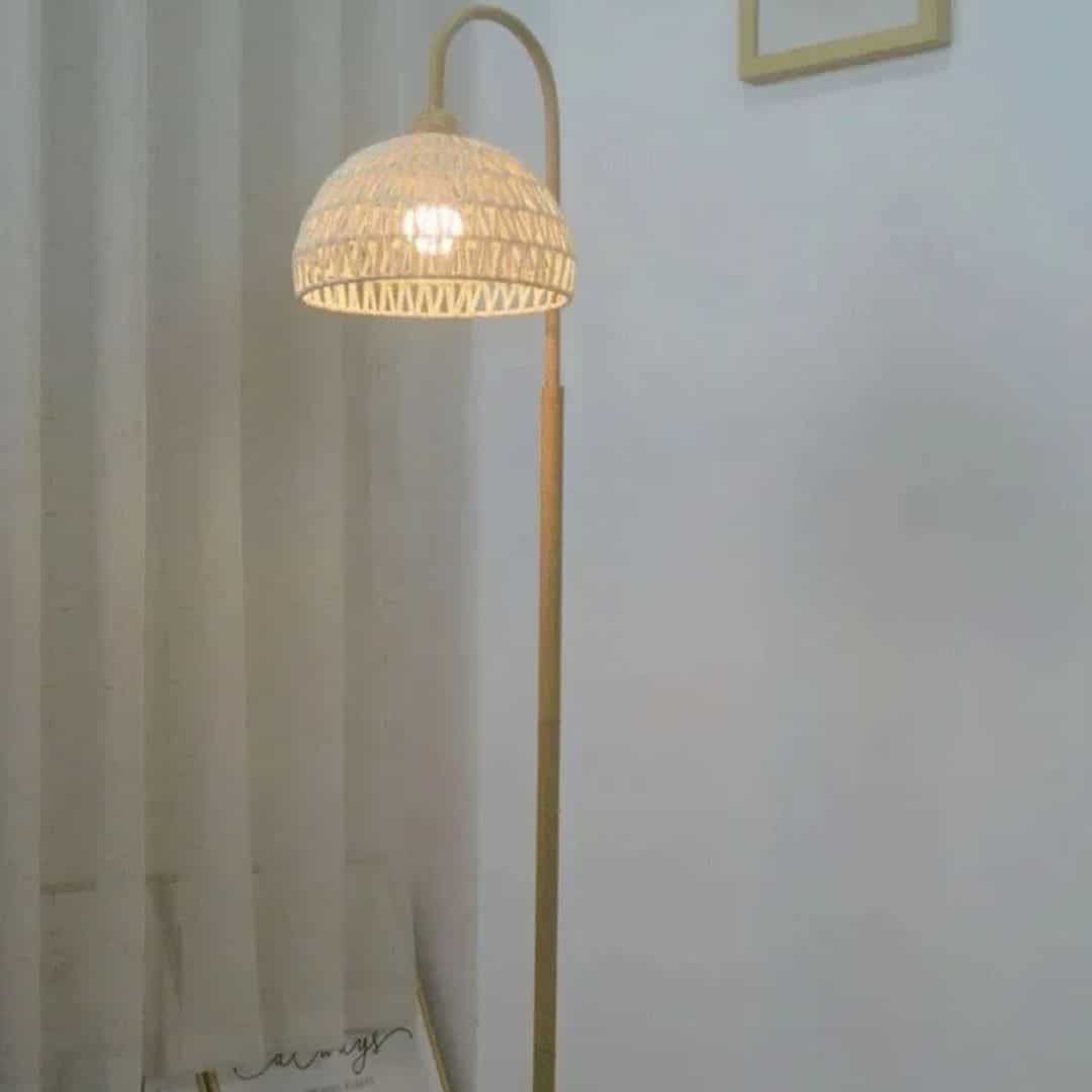 Minimalist rattan floor lamp with a slender stem and woven shade – shown in a room setting (2)