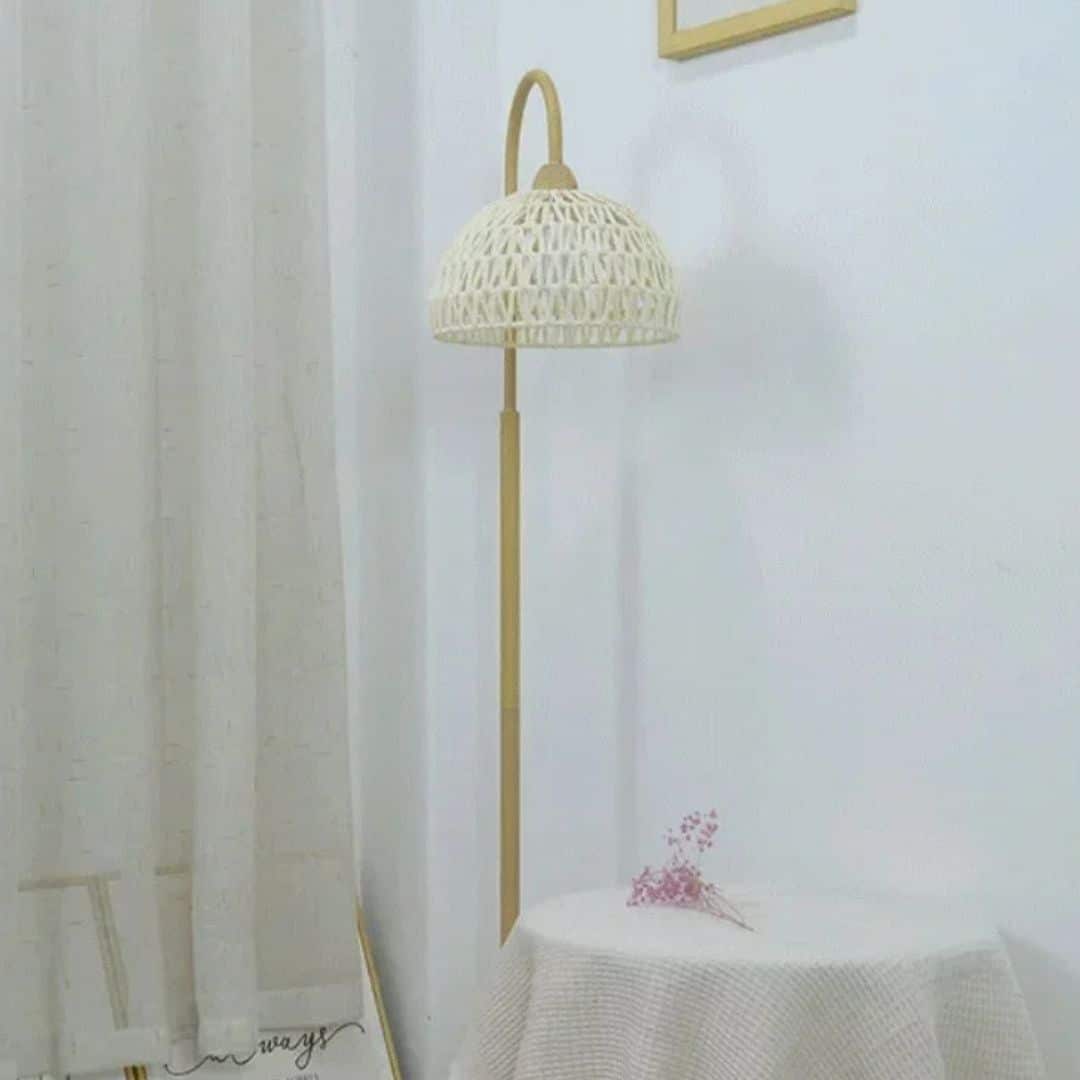 Minimalist rattan floor lamp with a slender stem and woven shade – shown in a room setting (3)