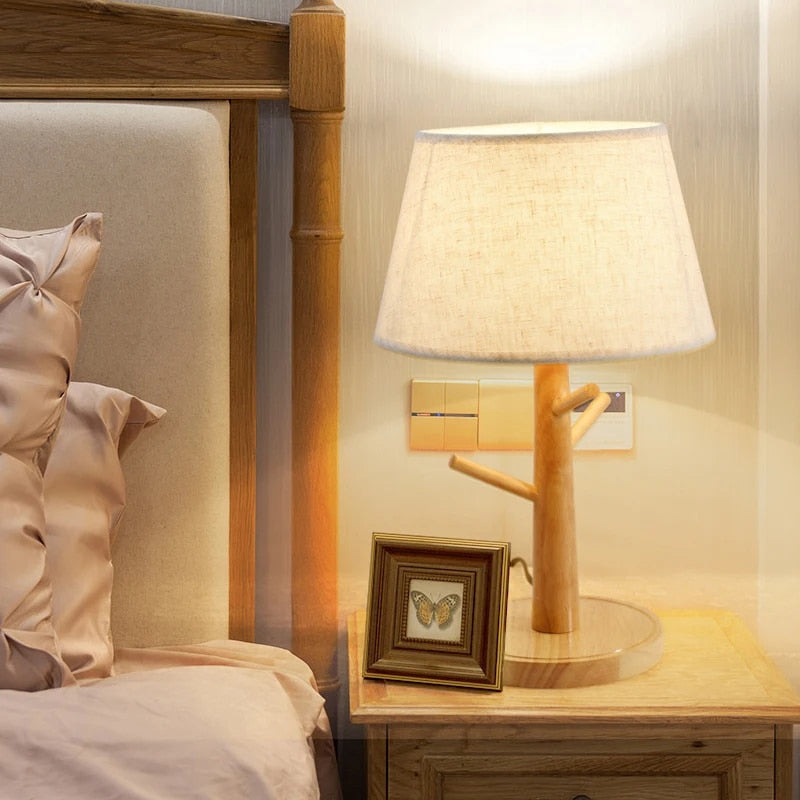 Natural wood LED bedside lamp with a fabric shade – shown lit in a room setting