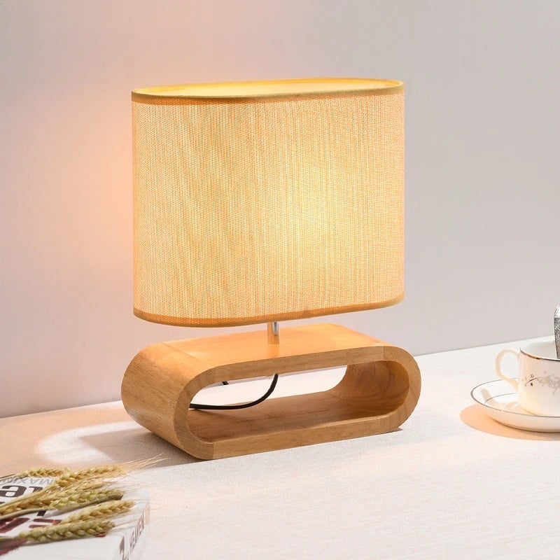 Rounded handwoven rattan bedside lamp in natural tones – shown lit