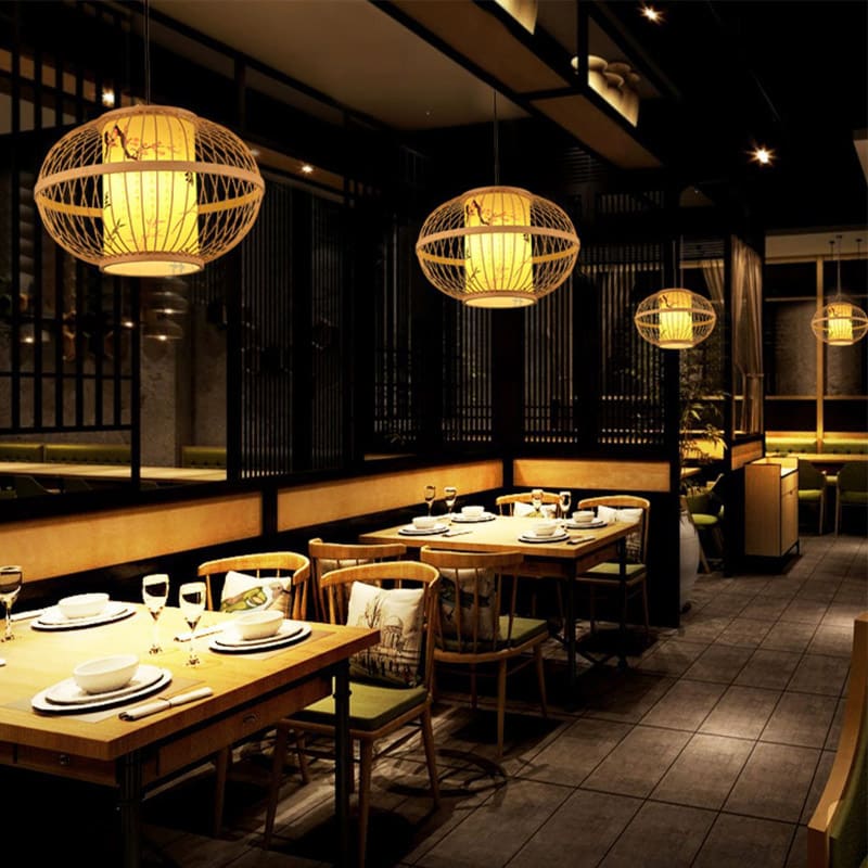 Handmade bamboo and rattan pendant light with a tight mesh – shown lit in a room setting