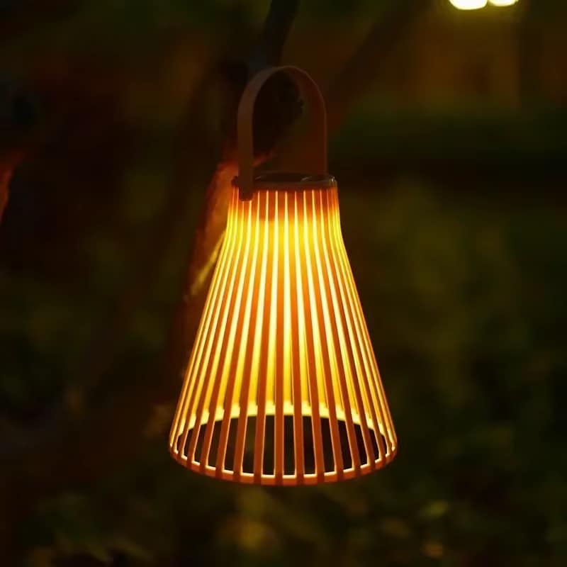 Colorful rattan-look aluminum solar lantern – orange variant, shown lit outdoors
