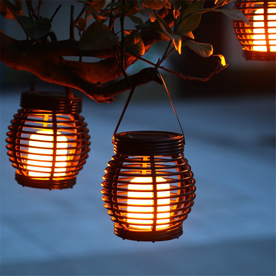Hanging handwoven solar rattan lantern with an integrated handle – shown lit outdoors (2)