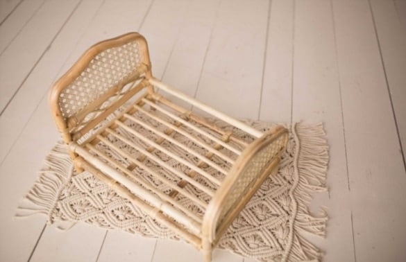 Braided rattan baby bed – white variant, shown in a room setting