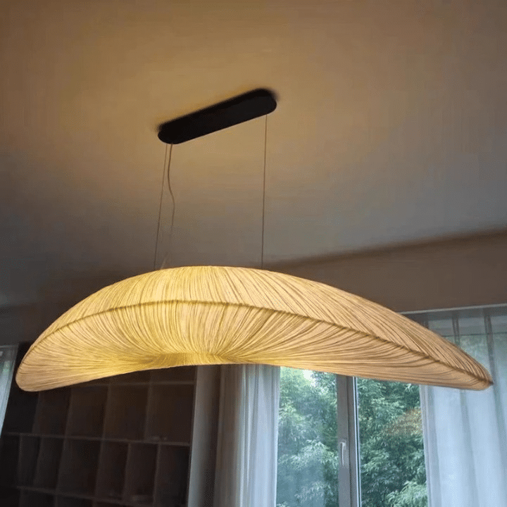 Hand-knit straw-look pendant light with golden fibers – shown lit in a room setting (2)