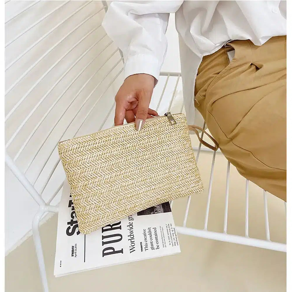 Woven rattan clutch with a brown strap – worn by a model