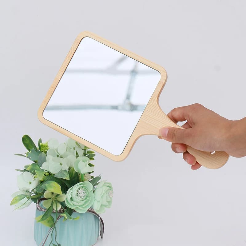 Square hand mirror with a turned wooden handle – shown in use