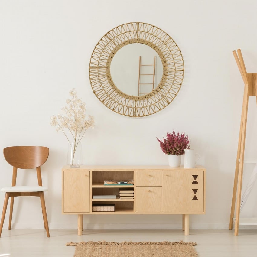 Natural rattan wall mirror with a tightly braided untreated frame – shown in a room setting