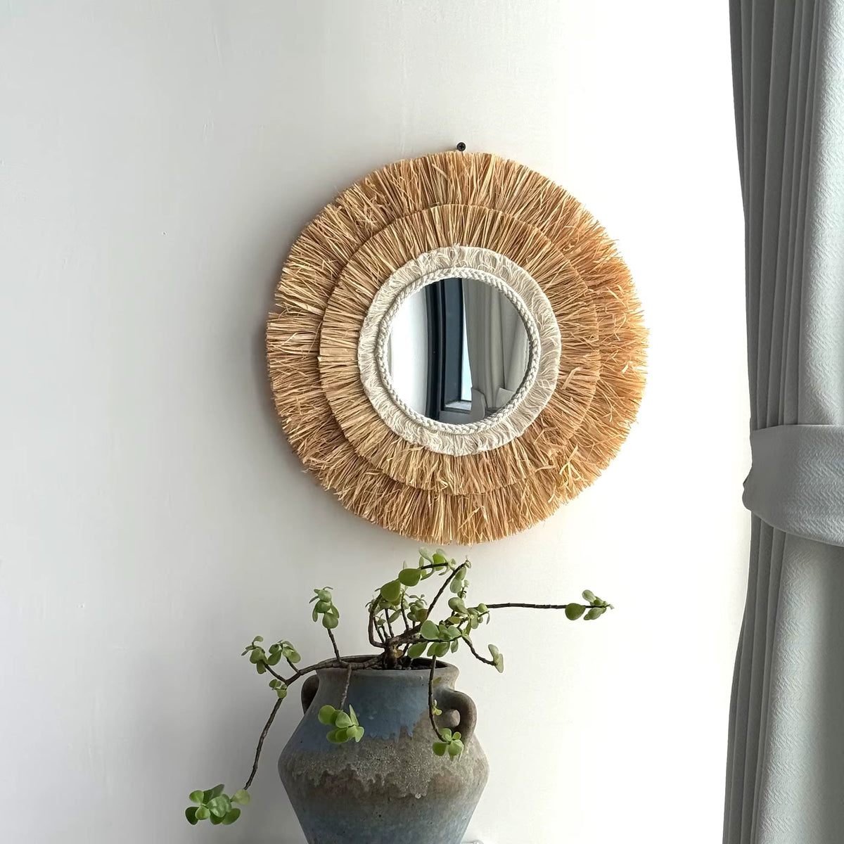 Circular natural straw mirror with an evenly woven frame – shown in a room setting