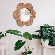 Natural rattan flower wall mirror with braided petals and a circular center – shown in a room setting