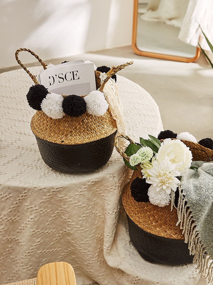 Black rattan basket with braided handles and black-and-white pompoms – shown in a room setting (2)