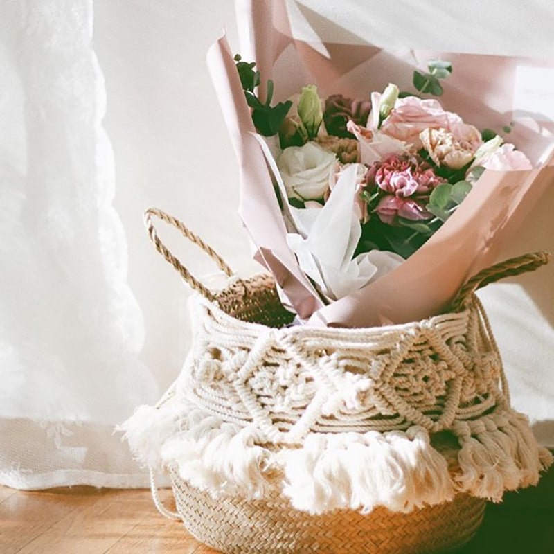 Decorative round rattan basket with a macramé pompom and fringe – shown in use