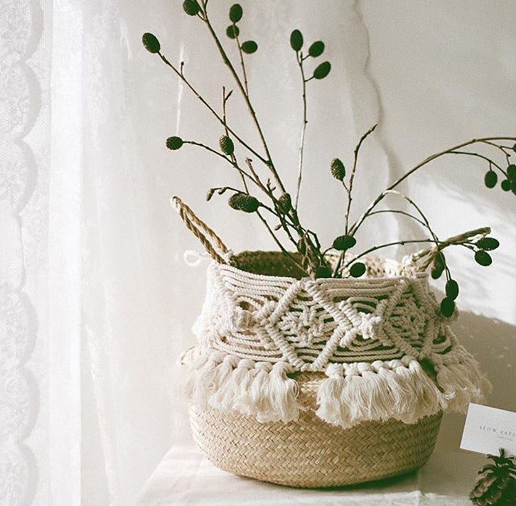 Decorative round rattan basket with a macramé pompom and fringe – shown in a room setting