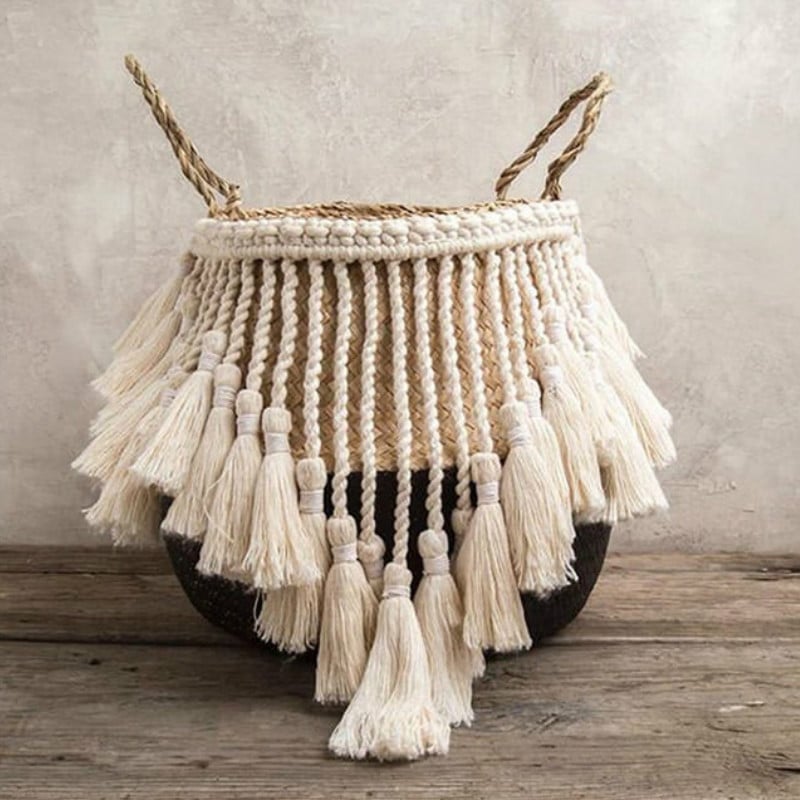 Black and beige wicker basket with a fringed border and white pompoms – shown in a room setting