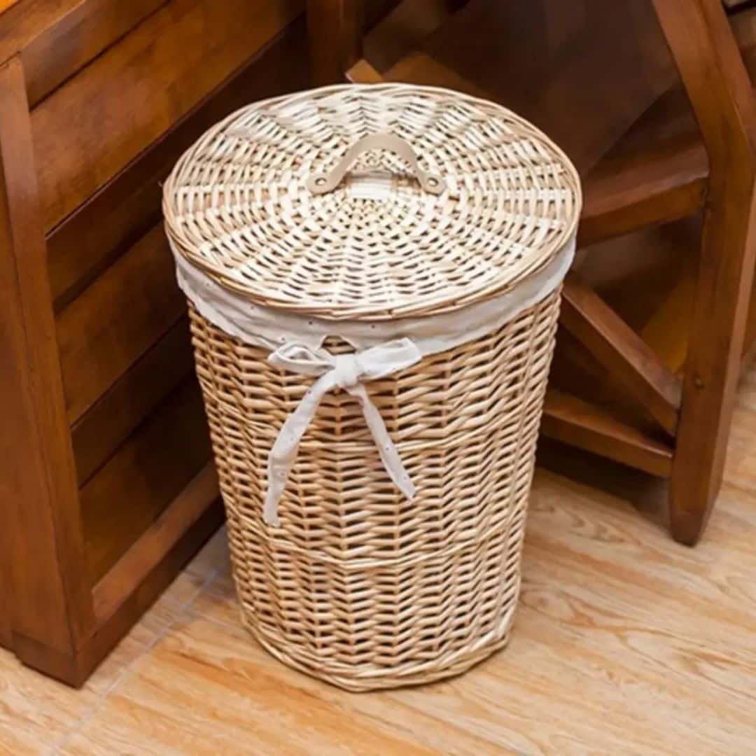 Round rattan laundry basket with a soft cotton lining – shown in a room setting (2)