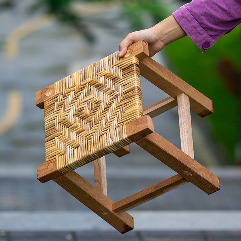 Small hand-braided rattan stool on a wooden frame – shown in use