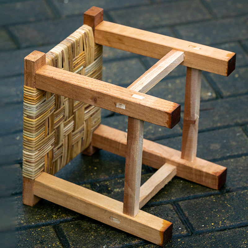 Small hand-braided rattan stool on a wooden frame – close-up detail